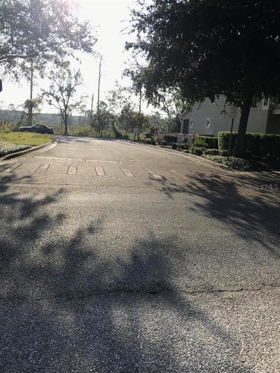 A paved residential street leads toward a building and trees under a bright sky — Parcel 1 - 607 OVIEDO BOULEVARD, OVIEDO, FL