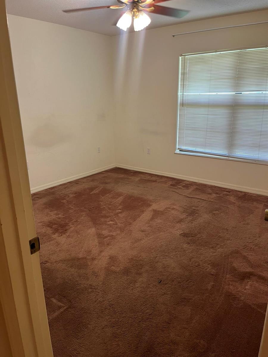 An empty bedroom features brown carpet, off-white walls, a ceiling fan, and a window — 8451 SW 14th Lane, Okeechobee FL 34974, OKEECHOBEE, FL
