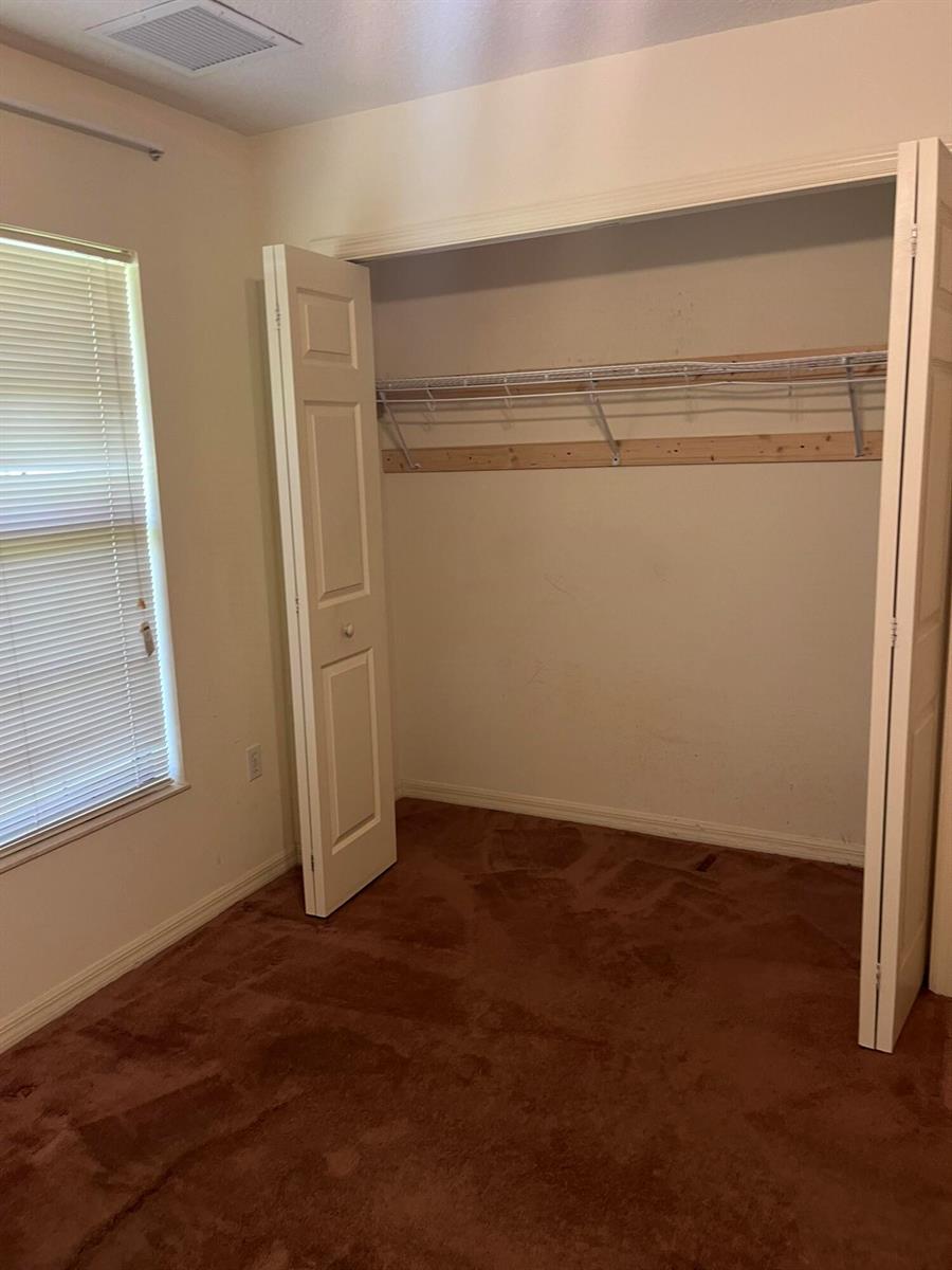 A bedroom with brown carpet, a window with blinds, and an open closet with shelving — 8451 SW 14th Lane, Okeechobee FL 34974, OKEECHOBEE, FL