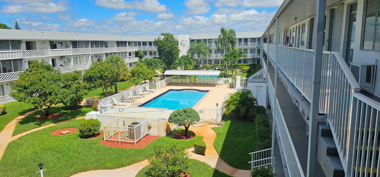 An elevated view of a swimming pool surrounded by apartment buildings and landscaped green space — 15610 NE 6th Avenue # 37b, Miami FL 33162, MIAMI, FL