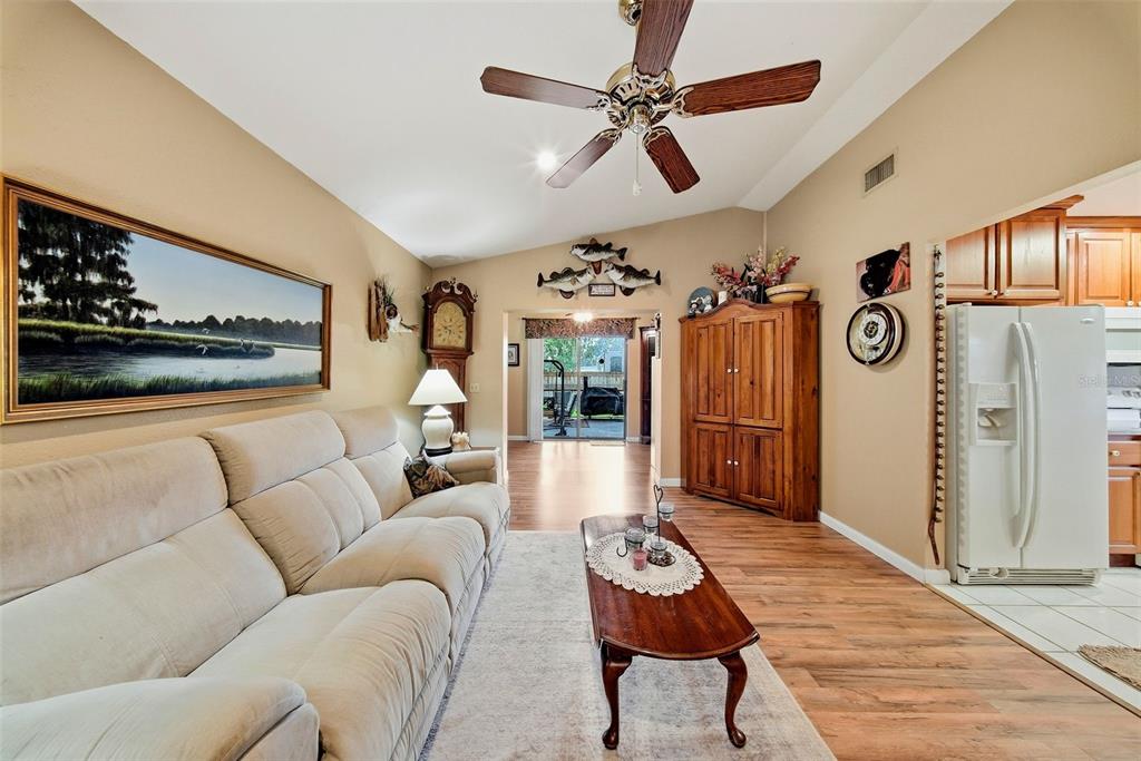 A living room features a beige sofa, wood flooring, a ceiling fan, and an adjacent kitchen — 38648 FERM CIRCLE, ZEPHYRHILLS, FL