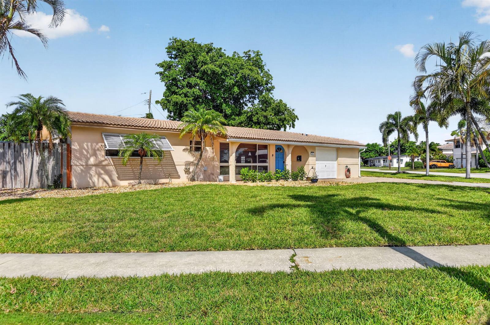 A single-story peach-colored house with a tiled roof, a blue front door, and palm trees — 301 SE 8th Avenue, Deerfield Beach FL 33441, DEERFIELD BEACH, FL