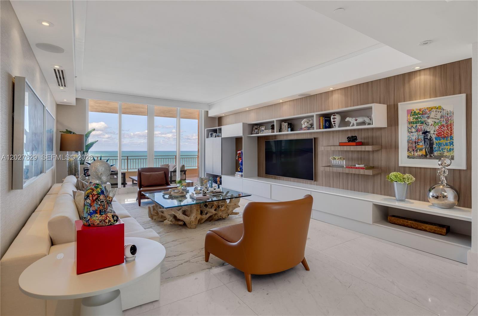 A modern living room features a glass-topped driftwood coffee table, leather chairs, and ocean views — 799 Crandon Blvd # 8, Key Biscayne FL 33149, KEY BISCAYNE, FL