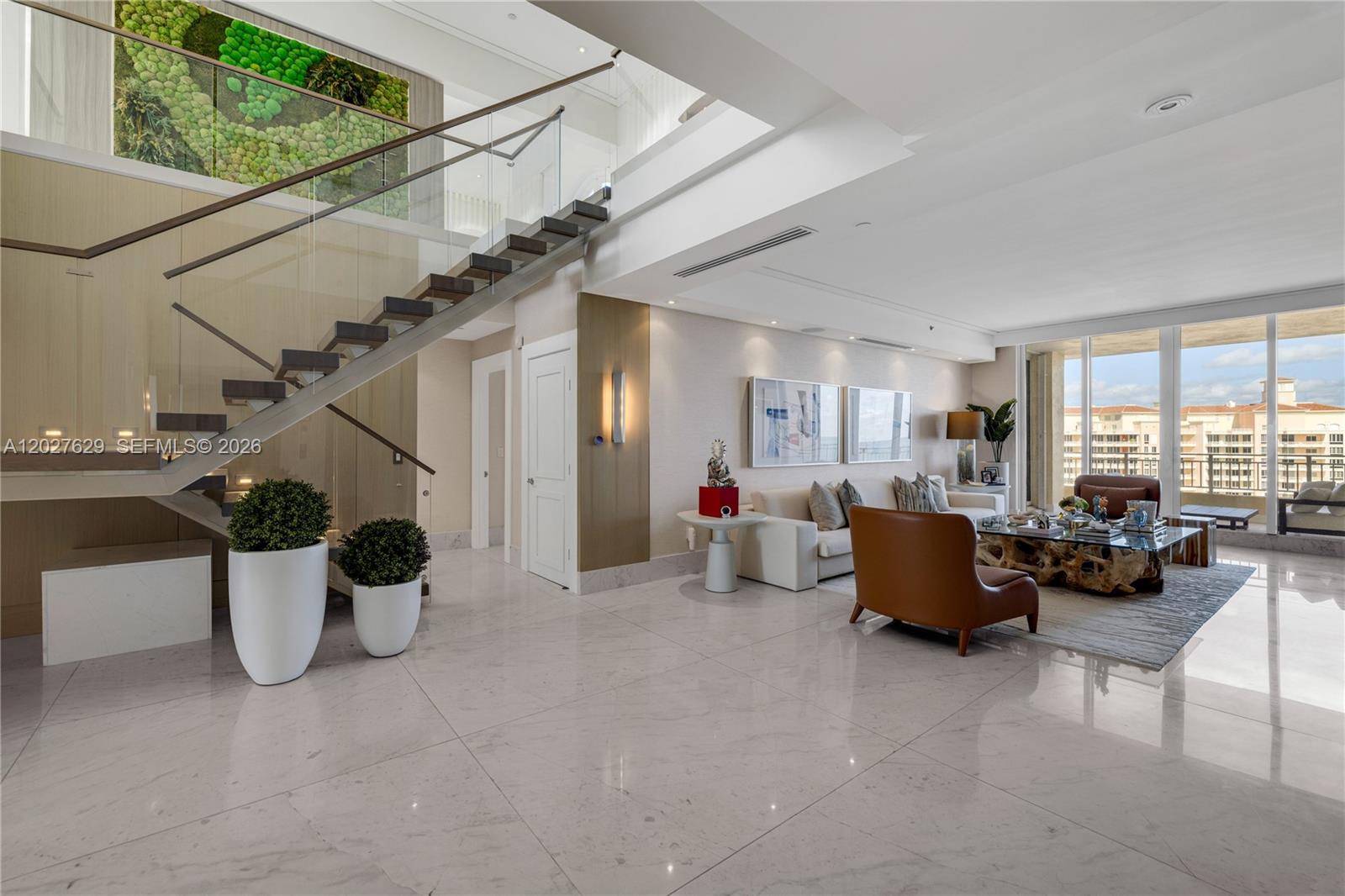 A modern living room features a floating staircase, marble floors, and floor-to-ceiling windows — 799 Crandon Blvd # 8, Key Biscayne FL 33149, KEY BISCAYNE, FL