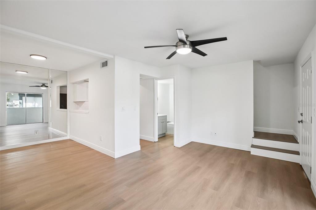 A bright living area features light wood-look flooring, a ceiling fan, and mirrored closet doors — 2906 LICHEN LANE UNIT B, CLEARWATER, FL