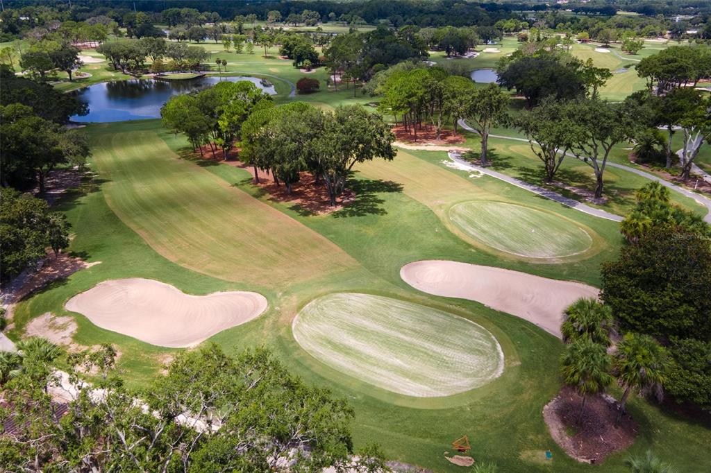 An aerial view of a golf course featuring a green, sand bunkers, and surrounding trees — 14 CAMINO REAL BOULEVARD UNIT 14, HOWEY IN THE HILLS, FL