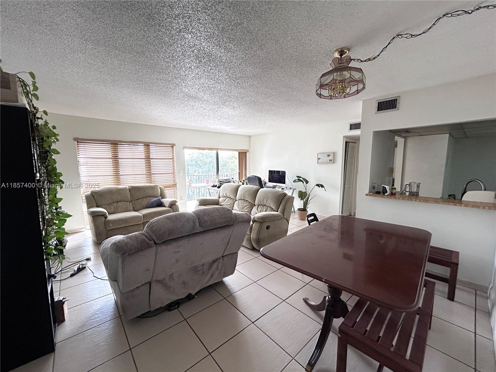 A living and dining area features tile flooring, a popcorn ceiling, and neutral walls — 14201 SW 66th St # 306, Miami FL 33183, MIAMI, FL