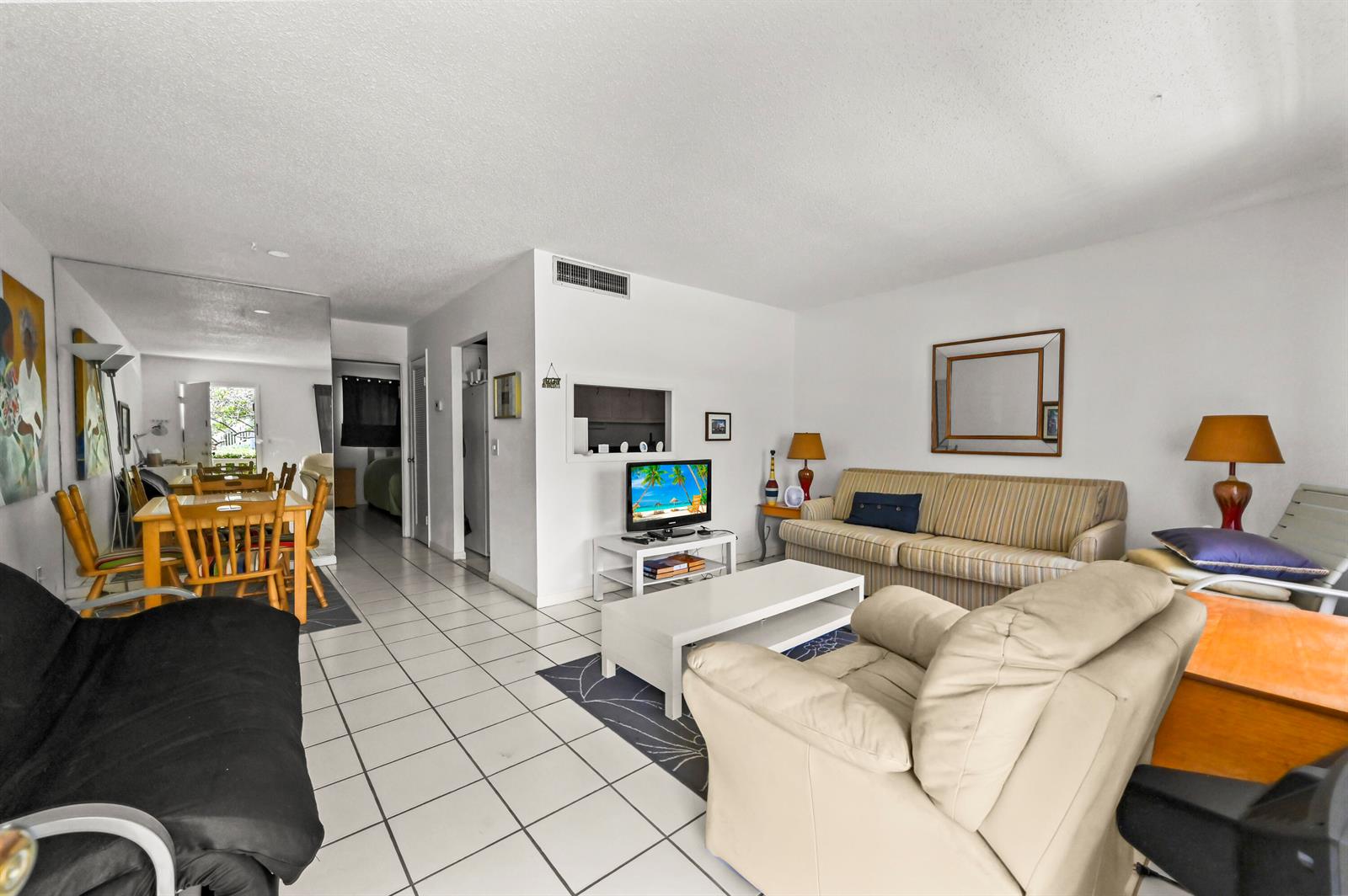 A living room with white tile floors, a striped sofa, and a beige armchair — 631 Snug Harbor Drive # S1, Boynton Beach FL 33435, BOYNTON BEACH, FL
