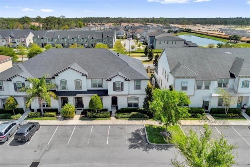 An aerial view shows two multi-story townhomes with parking spaces in the foreground — 1549 CAREY PALM CIRCLE, KISSIMMEE, FL