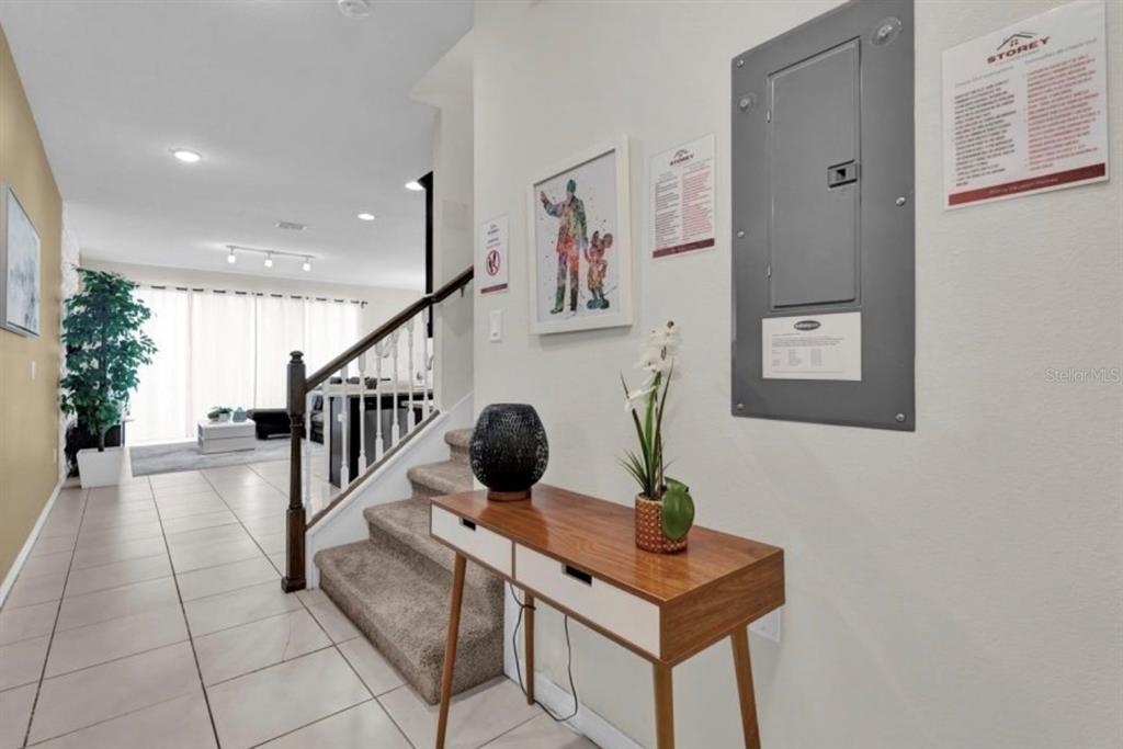 A hallway features a console table, a staircase, and an electrical panel on the wall — 1549 CAREY PALM CIRCLE, KISSIMMEE, FL