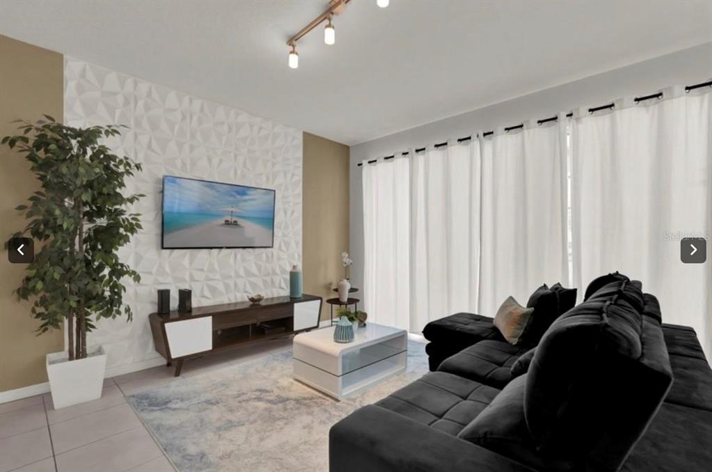 A living room features a textured white accent wall, a dark media console, and black sofa — 1549 CAREY PALM CIRCLE, KISSIMMEE, FL