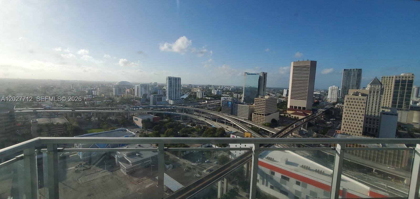 An elevated view from a balcony overlooks a city skyline with highways and tall buildings — 90 SW 3rd St # 2705, Miami FL 33130, MIAMI, FL