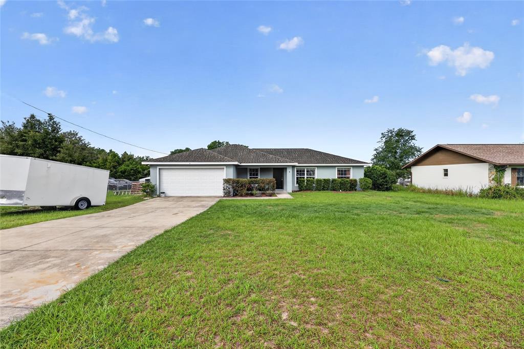 A single-story house with a white garage door, concrete driveway, and a large front lawn — 8 ALMOND DRIVE TRACE, OCALA, FL
