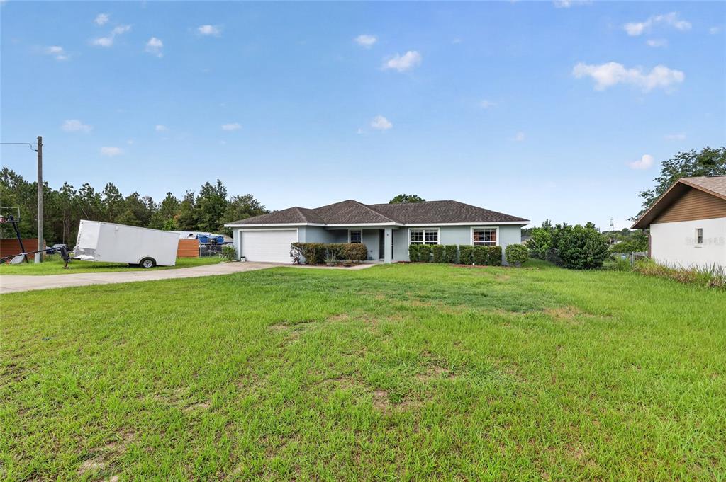 A single-story house with a light-colored exterior, a two-car garage, and a large front lawn — 8 ALMOND DRIVE TRACE, OCALA, FL