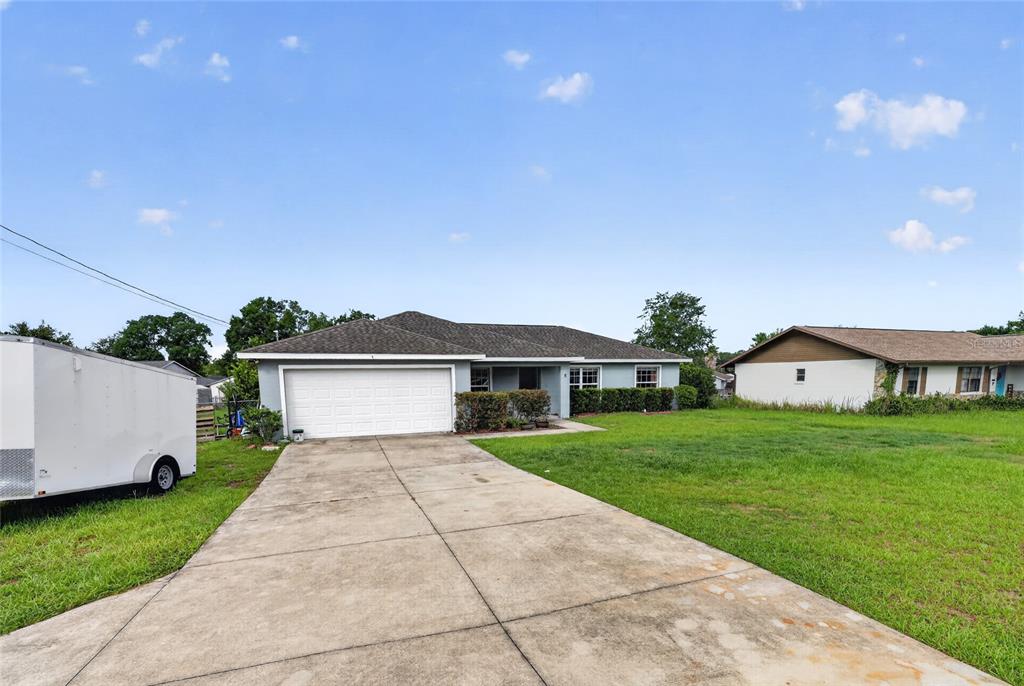 A single-story house with a white garage door, concrete driveway, and a large grassy yard — 8 ALMOND DRIVE TRACE, OCALA, FL