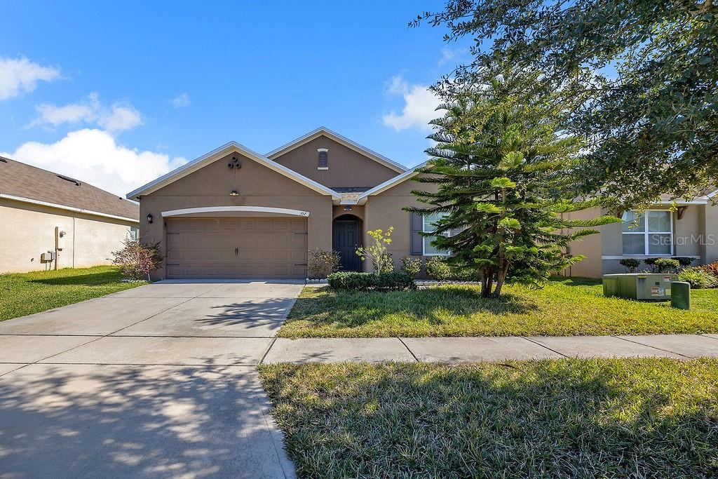 A single-story suburban house with a tan stucco exterior, a two-car garage, and a driveway — 397 ABERDEEN DRIVE, DAVENPORT, FL