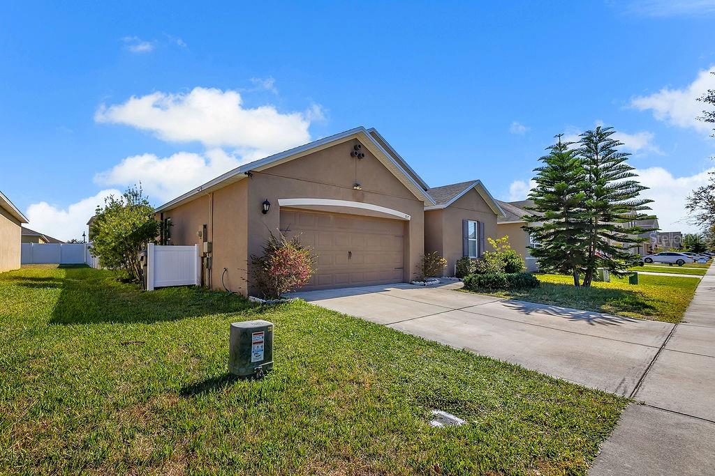 A tan single-story house with a two-car garage and a concrete driveway under a blue sky — 397 ABERDEEN DRIVE, DAVENPORT, FL