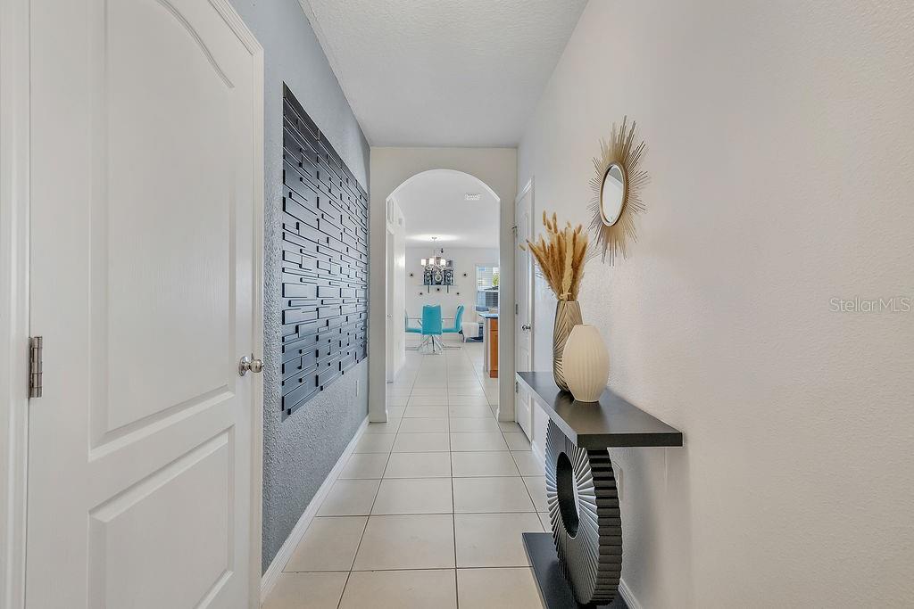 A hallway with tiled floors leads to a dining area through an arched doorway — 397 ABERDEEN DRIVE, DAVENPORT, FL