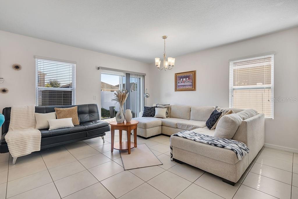 A living room features a black sofa, a beige sectional, a round table, and tile flooring — 397 ABERDEEN DRIVE, DAVENPORT, FL