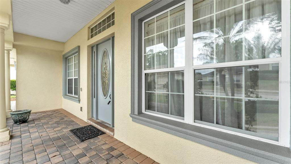 A front porch with a paved floor, a light blue front door, and a large window — 3940 SUNNYWOOD CIRCLE, LAKELAND, FL