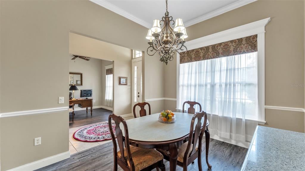 A dining area features a wooden table, chandelier, and a view into an adjacent office — 3940 SUNNYWOOD CIRCLE, LAKELAND, FL