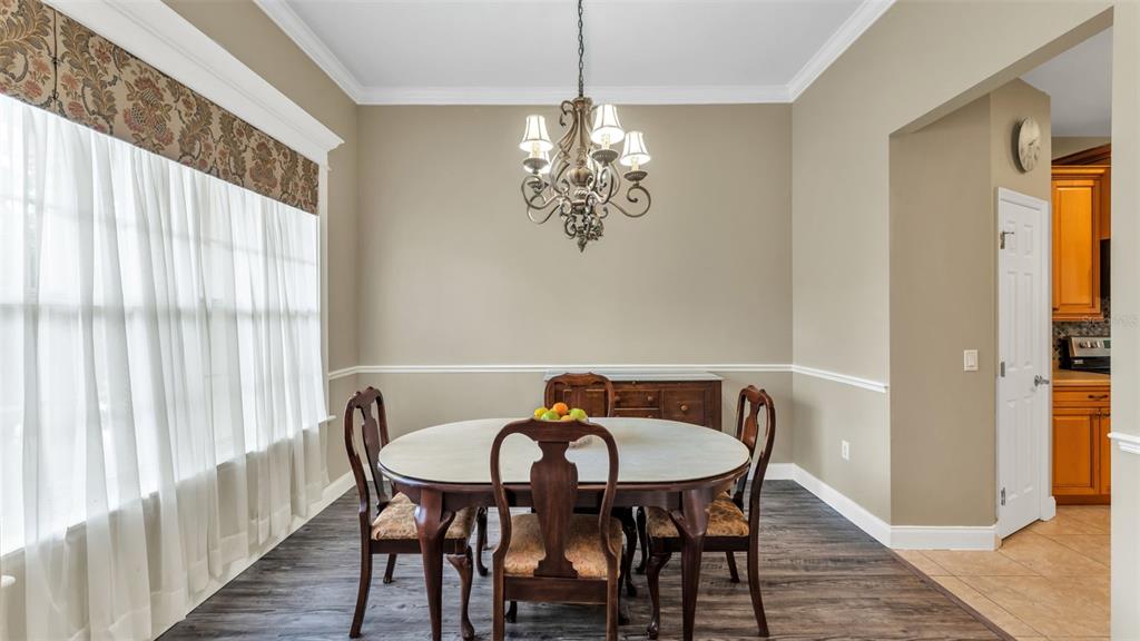 A dining room features a wooden table, four chairs, a chandelier, and wood-look flooring — 3940 SUNNYWOOD CIRCLE, LAKELAND, FL