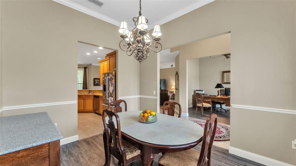 A dining area features a round table, a chandelier, and views into a kitchen and office — 3940 SUNNYWOOD CIRCLE, LAKELAND, FL