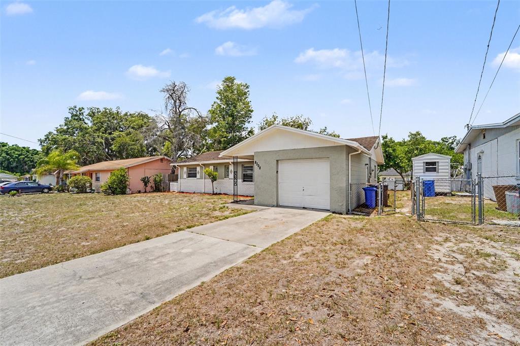 A single-story house with a concrete driveway, a front-facing garage, and a chain-link fence — 8308 OLEANDER LANE, TAMPA, FL