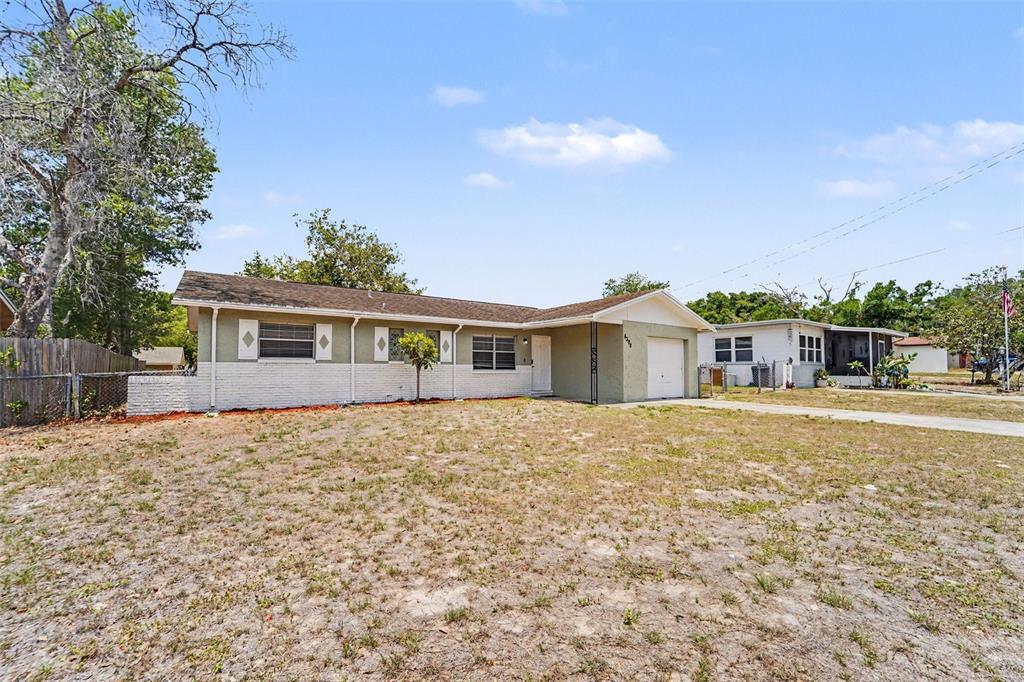 A single-story house with a white brick base, green siding, and an attached garage — 8308 OLEANDER LANE, TAMPA, FL