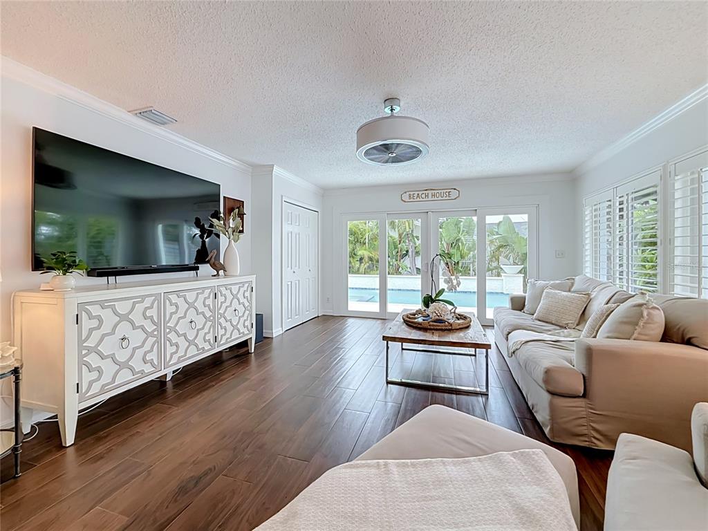 A living room features dark wood floors, a white media console, and sliding glass doors — 2931 ALTON DRIVE, ST PETE BEACH, FL