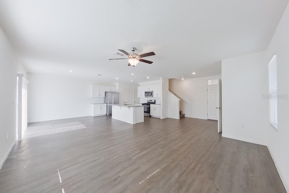 An open-concept living area features a kitchen with white cabinetry, an island, and wood-look flooring — 32048 KATELIN CIRCLE, LEESBURG, FL