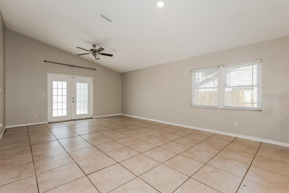 A living room features light-colored tile flooring, a vaulted ceiling with a fan, and French doors — 2027 HELM LANE, VALRICO, FL