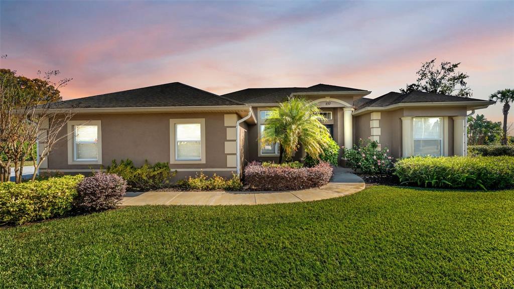 A single-story house with a tan stucco exterior, a dark roof, and a landscaped yard — 237 KENT COURT, HAINES CITY, FL
