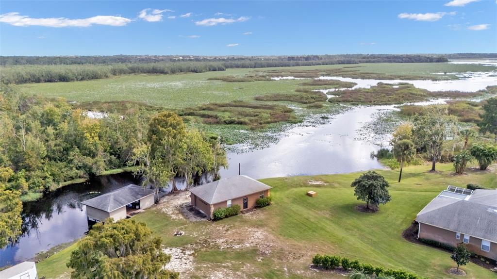 An aerial view shows two houses situated on a grassy lot beside a marshy lake — 237 KENT COURT, HAINES CITY, FL