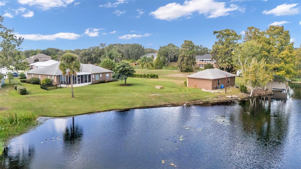 An aerial view shows two houses situated on a grassy lot beside a pond — 237 KENT COURT, HAINES CITY, FL