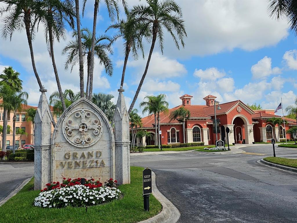 A stone monument sign for Grand Venezia stands before a red-roofed building and palm trees — 2713 VIA MURANO UNIT 236, CLEARWATER, FL