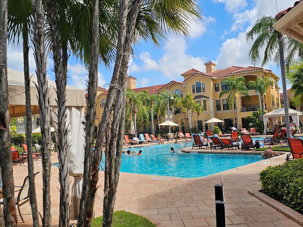 A swimming pool surrounded by lounge chairs and palm trees in front of a large building — 2713 VIA MURANO UNIT 236, CLEARWATER, FL