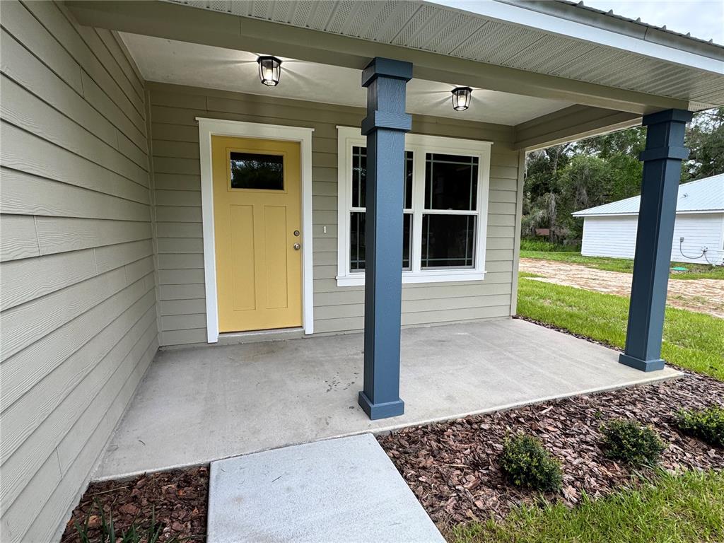 A front porch features a yellow door, dark blue columns, and light green siding — 8523 SE 70TH AVENUE, TRENTON, FL