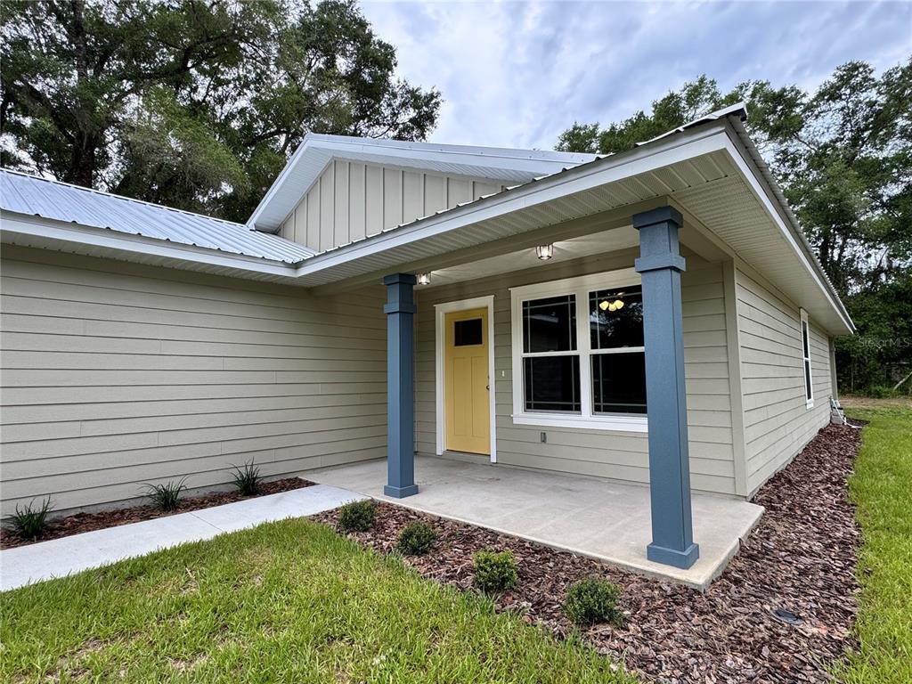 A single-story house with light green siding, a yellow front door, and blue porch columns — 8523 SE 70TH AVENUE, TRENTON, FL