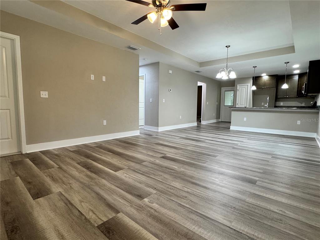 An open-concept living area features wood-look flooring, neutral walls, and a kitchen with pendant lighting — 8523 SE 70TH AVENUE, TRENTON, FL