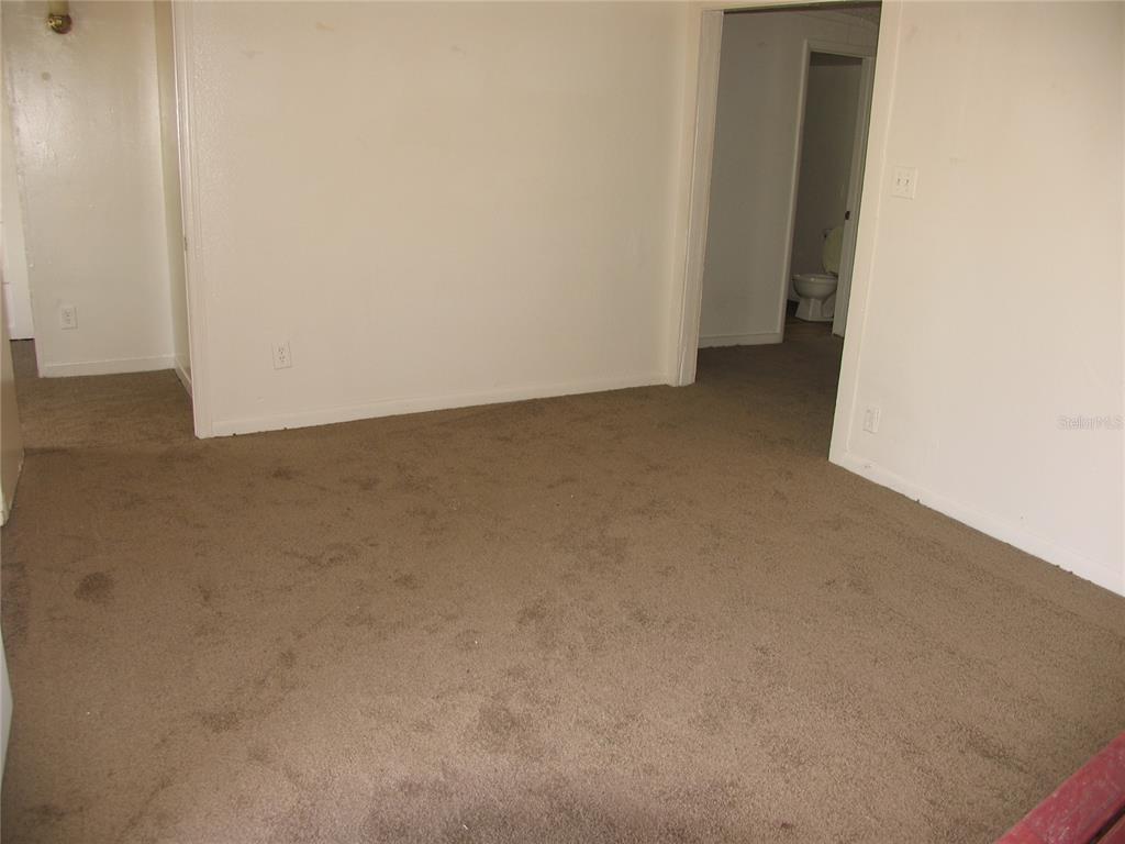 An interior view of a carpeted room with white walls and a doorway leading to a bathroom — 1020 AVONDALE AVENUE, ORLANDO, FL