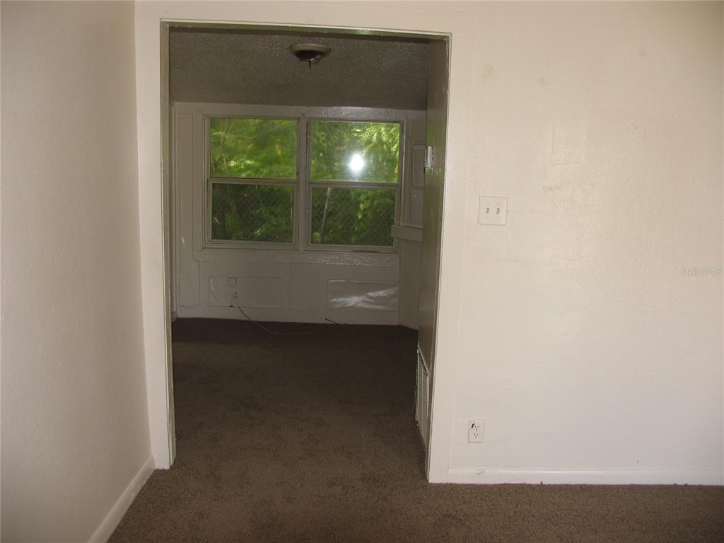 A view through a doorway shows a carpeted room with windows looking out onto greenery — 1020 AVONDALE AVENUE, ORLANDO, FL