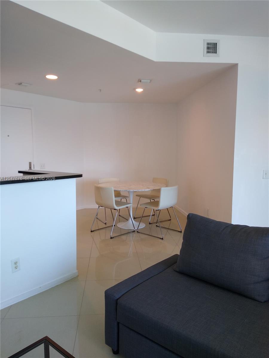 A dining area with a round table and four chairs sits adjacent to a kitchen counter — 300 S Biscayne Blvd # 2905, Miami FL 33131, MIAMI, FL