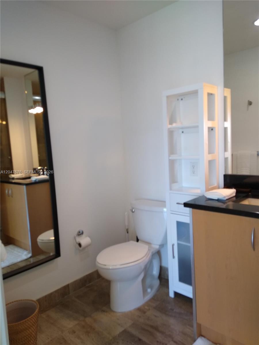 A bathroom features a toilet, a white storage unit, and a vanity with a black countertop — 300 S Biscayne Blvd # 2905, Miami FL 33131, MIAMI, FL