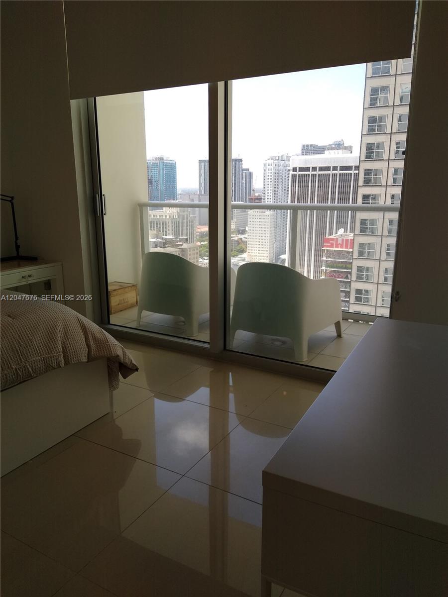 A bedroom with tile flooring features a sliding glass door leading to a balcony — 300 S Biscayne Blvd # 2905, Miami FL 33131, MIAMI, FL