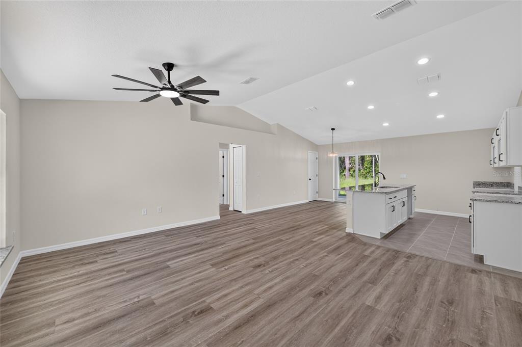 An open-concept living area with wood-look flooring, a kitchen island, and recessed ceiling lighting — 6 BAY PASS TERRACE, OCKLAWAHA, FL