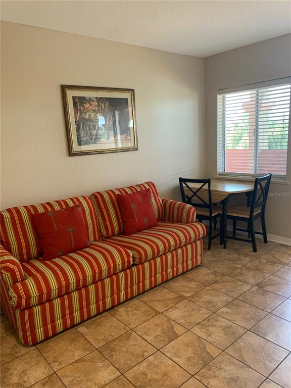 A room features a striped sofa, a small dining table with two chairs, and tile flooring — 2777 N POINCIANA BOULEVARD UNIT 226G, KISSIMMEE, FL