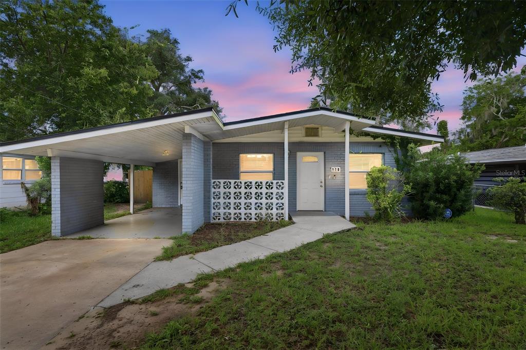 A single-story gray brick house features a carport, a decorative breeze block wall, and lawn — 216 GRAHAM STREET, DAYTONA BEACH, FL