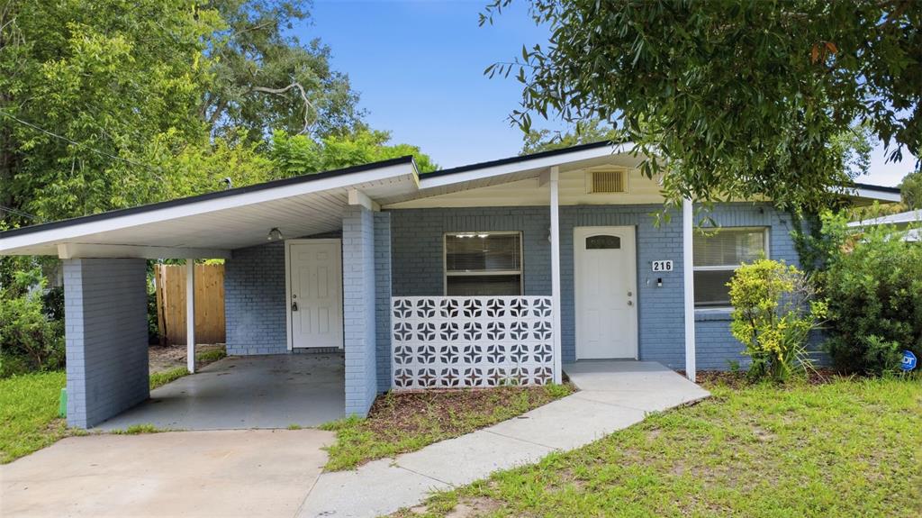 A single-story blue brick house features a carport, a decorative screen wall, and a walkway — 216 GRAHAM STREET, DAYTONA BEACH, FL