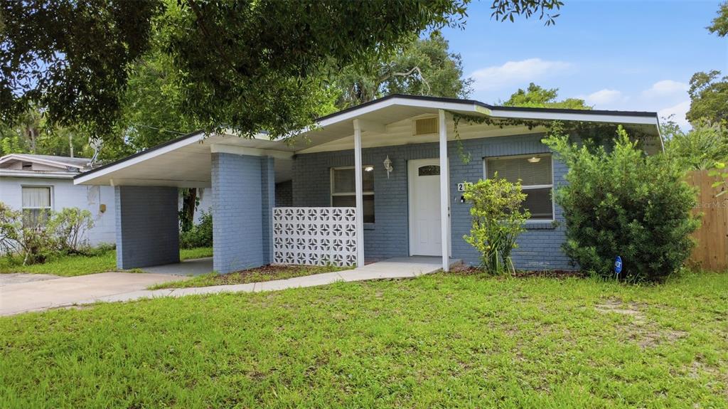 A single-story blue brick house with a carport and a decorative breeze block privacy screen — 216 GRAHAM STREET, DAYTONA BEACH, FL